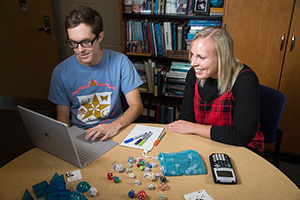 students working at table with computer and game pieces